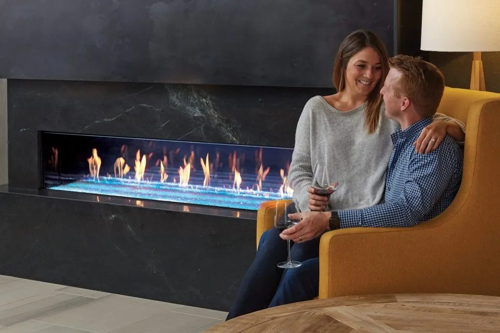 Couple relaxing by a long linear gas fireplace